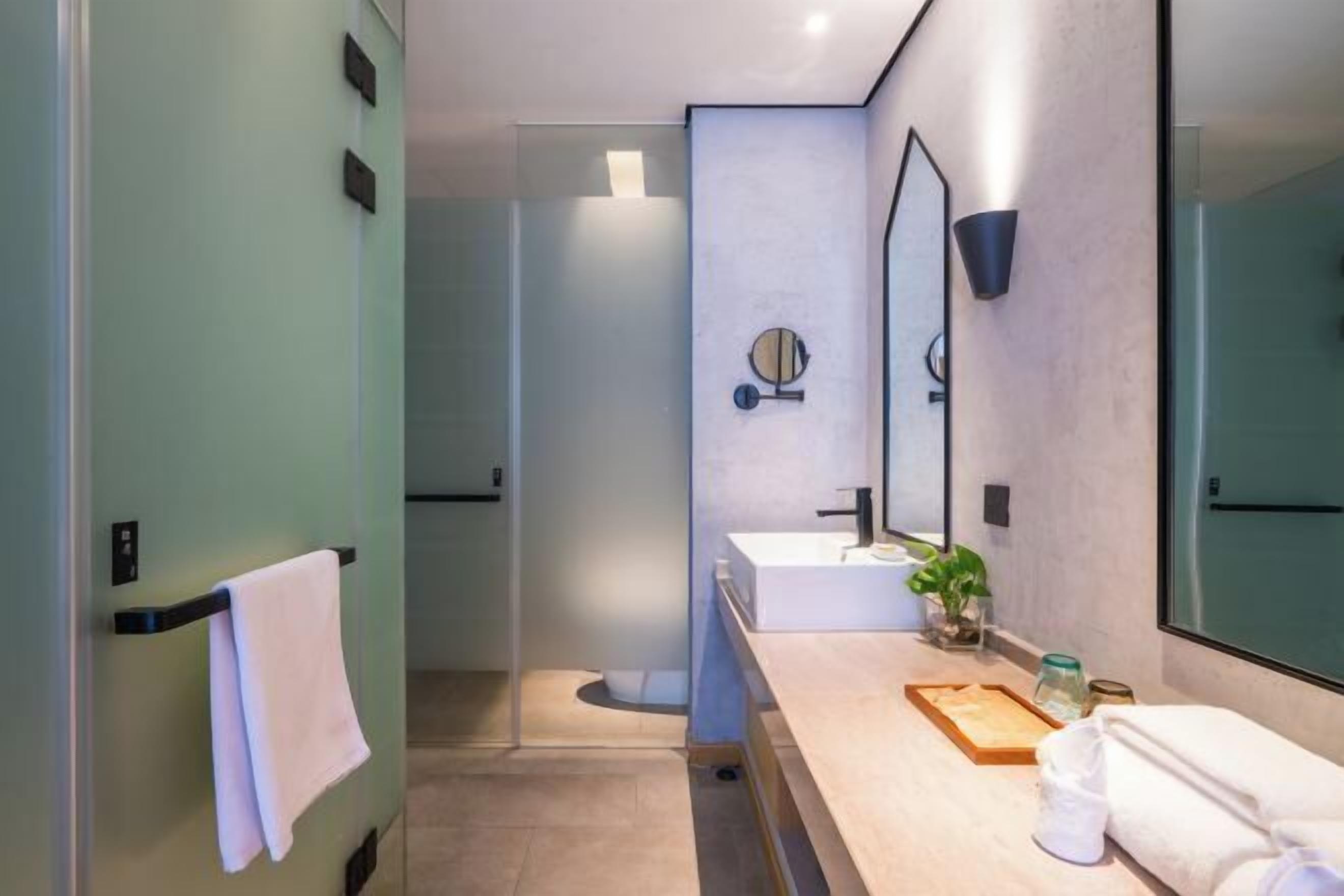 A modern bathroom with a large mirror, a sink, and a towel rack.