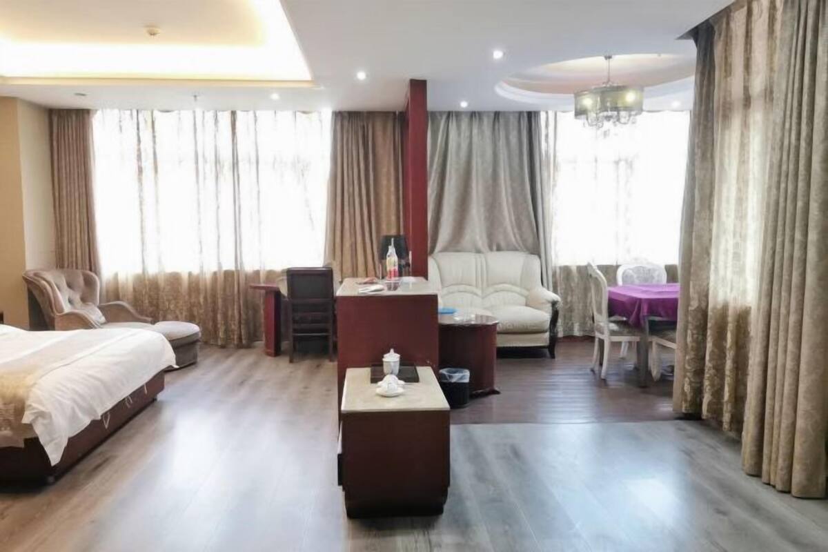 A hotel room with a bed, a desk, a chair, a small table, and a dining area.