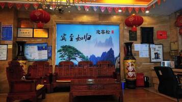 A traditional Chinese-style room with wooden furniture, a large wall-mounted screen, and red lanterns.
