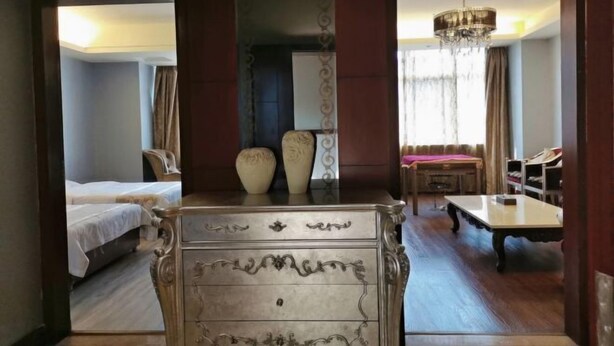 Quarto de hotel com cama, cômoda, mesa e lustre.