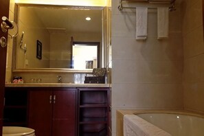 A bathroom with a large mirror, a bathtub, and a sink. - Xingkai Garden Hotel (Panzhou)