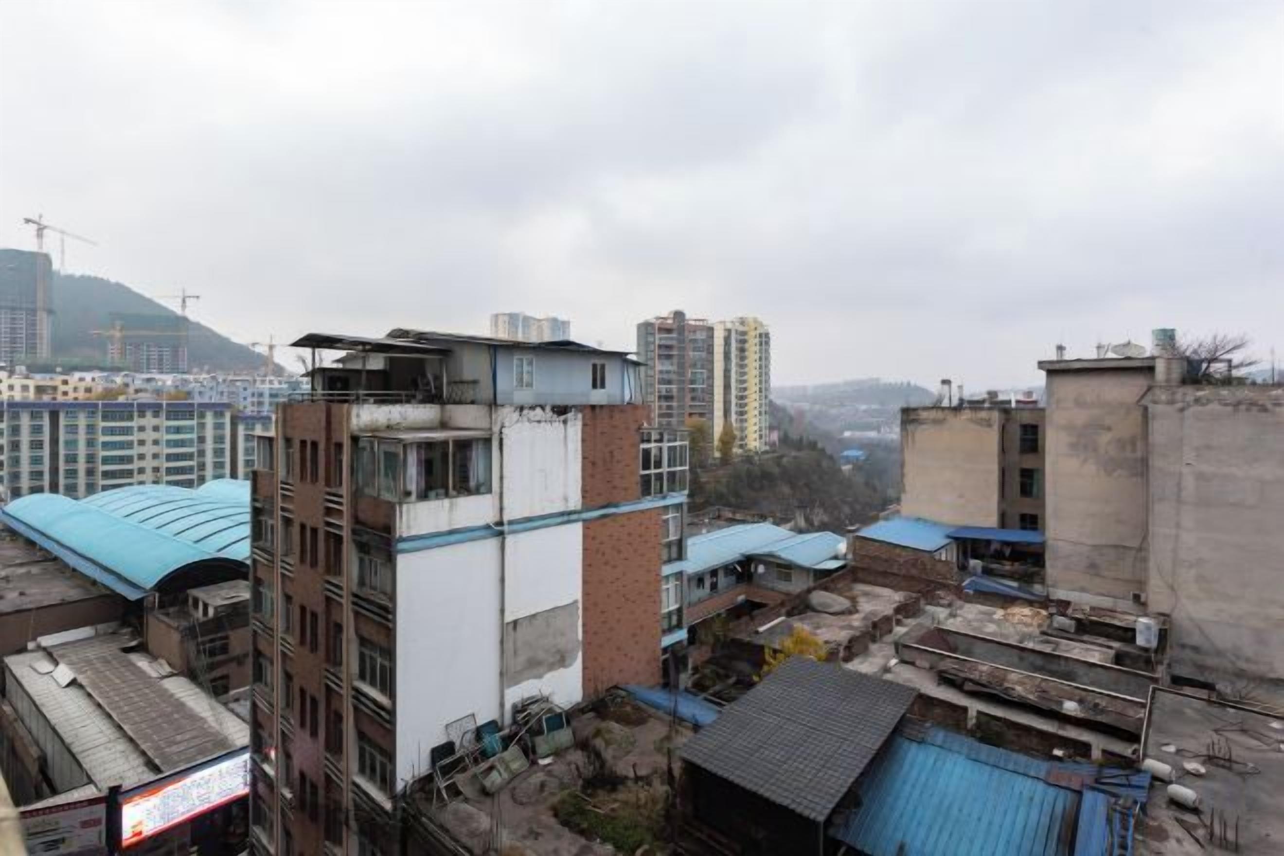 Un immeuble de grande hauteur, doté de nombreux étages, comprenant des logements et des espaces commerciaux, avec une grue de construction visible en arrière-plan.
