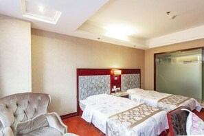 A hotel room with two beds, a chair, a nightstand, and a wall-mounted lamp. - Xingkai Garden Hotel (Panzhou)
