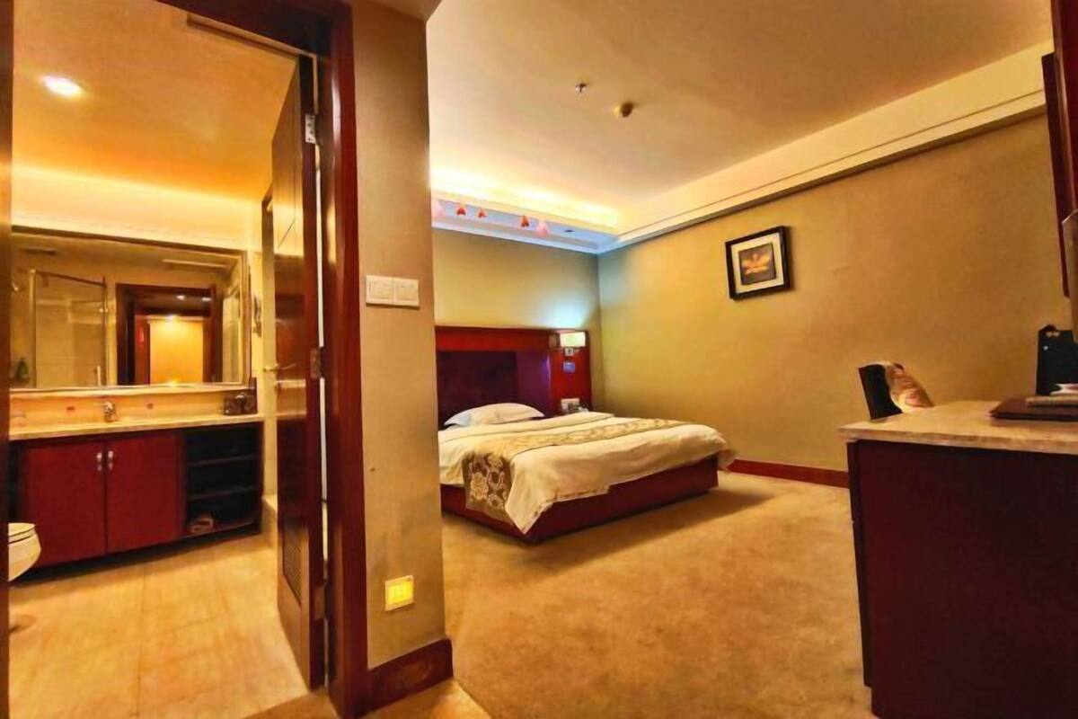 A hotel room with a bed, a desk, a mirror, and a bathroom.