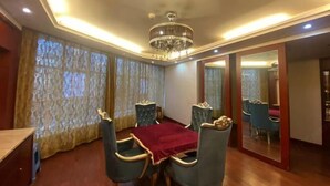 Uma sala de jantar com candelabro, cortinas e espelho.