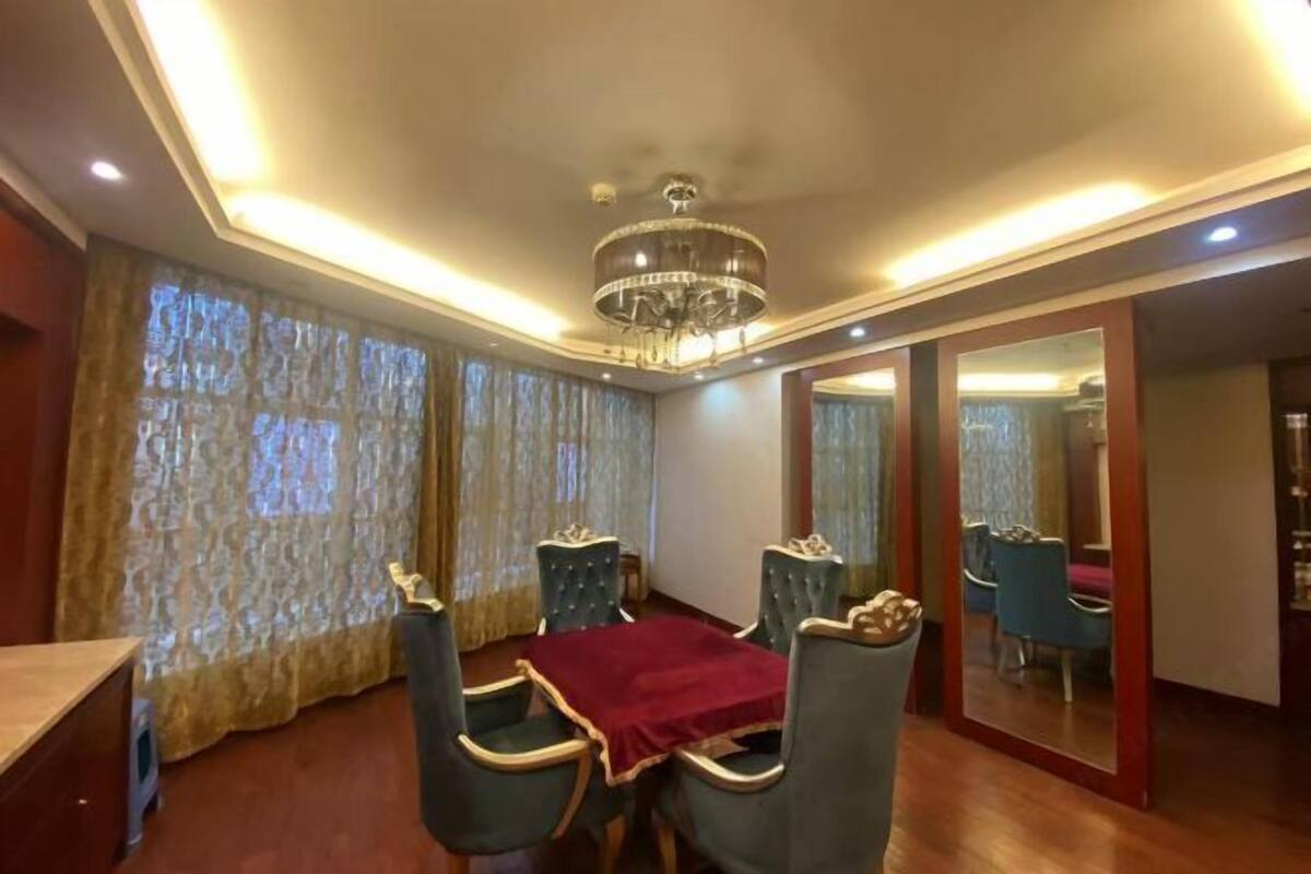 A dining area with a chandelier, curtains, and a mirror.