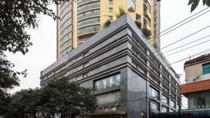 Edifício de vários andares com design moderno, destacando uma entrada imponente e uma placa visível.