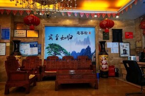 A traditional Chinese-style lobby with wooden furniture, red lanterns, and a large poster with Chinese calligraphy.