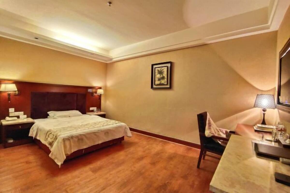 A hotel room with a bed, bedside tables, a desk, and a chair.