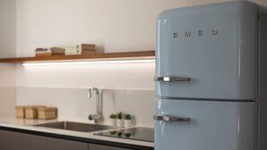 A modern kitchen with a light blue refrigerator, a stainless steel sink, and a wooden shelf above the counter. - WeLive Trapani - Superior Second Floor Apartment (Trapani)