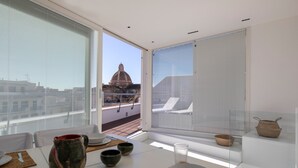 A modern dining area with a table set for two, a view of a dome structure, and a balcony with a railing. - WeLive Trapani - Penthouse apartment with terrace and Jacuzzi (Trapani)