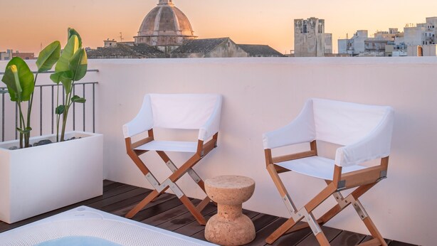 A rooftop terrace with a hot tub, two white cushioned chairs, a small round table, and a potted plant. - WeLive Trapani - Penthouse apartment with terrace and Jacuzzi (Trapani)