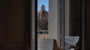 A view of a large dome building through a window, with a chair and table visible in the foreground. - WeLive Trapani - Penthouse apartment with terrace and Jacuzzi (Trapani)