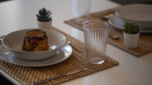 Une table avec une assiette de nourriture, un verre d’eau et deux petites plantes en pot.