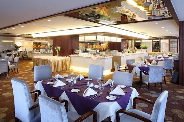 A modern restaurant with round tables set for dining, a bar area, and a kitchen in the background. - Taishan Gaoye Hotel (Taishan)