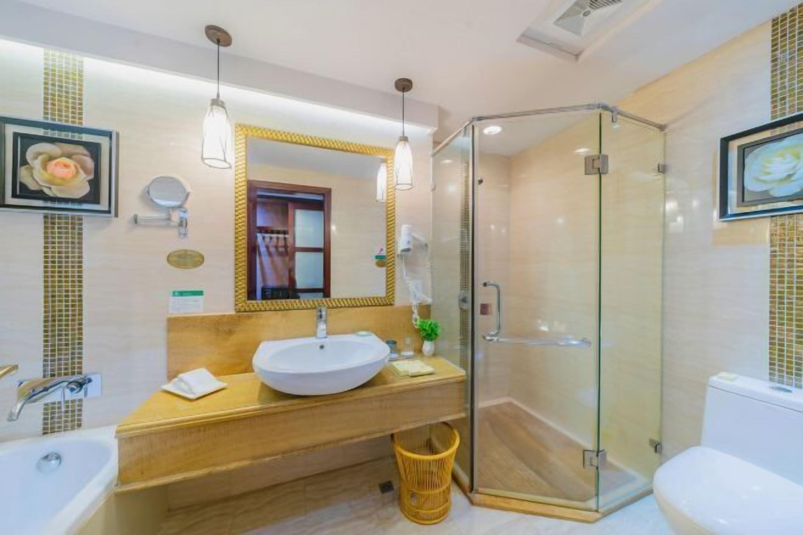 Un baño moderno con ducha envuelta en vidrio, tocador de madera y un espejo grande.