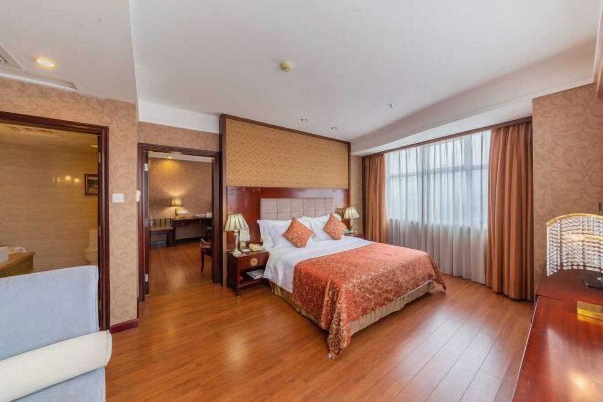 Habitación de hotel con una cama grande, mesitas de noche, un escritorio y vistas al exterior.