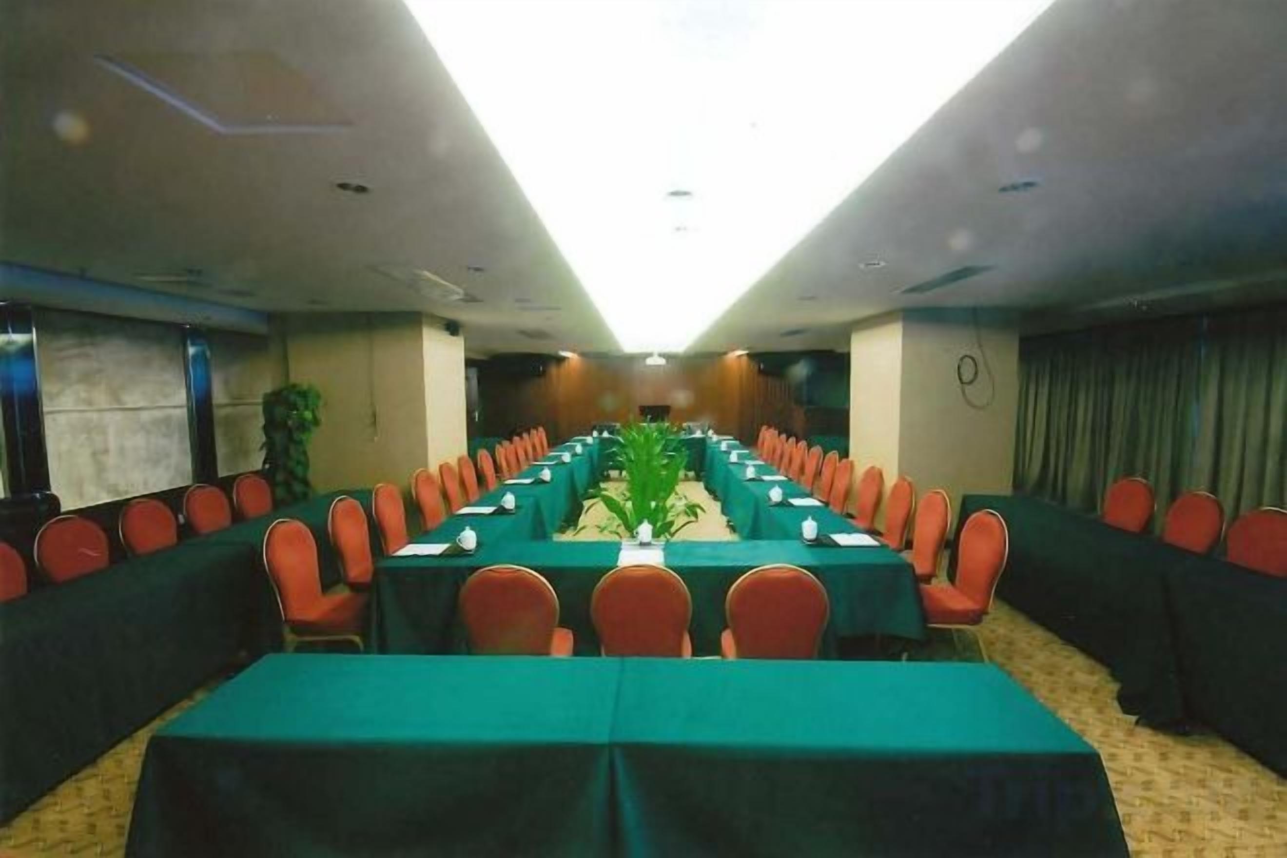 Une salle de conférence avec de longues tables et des chaises, une grande plante et une vue sur le plafond.