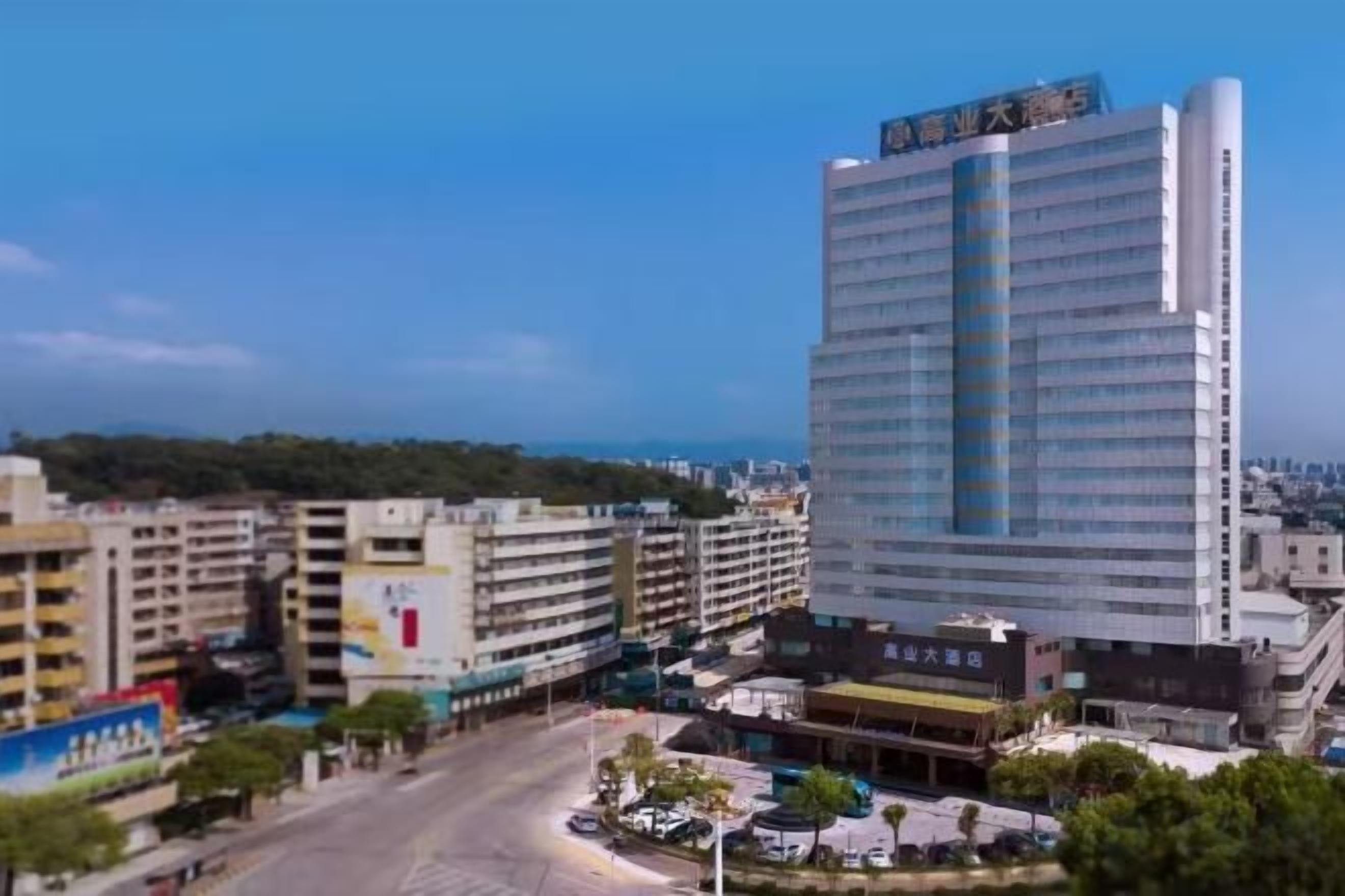 A high-rise hotel with multiple floors, surrounded by other buildings, and a clear sky.