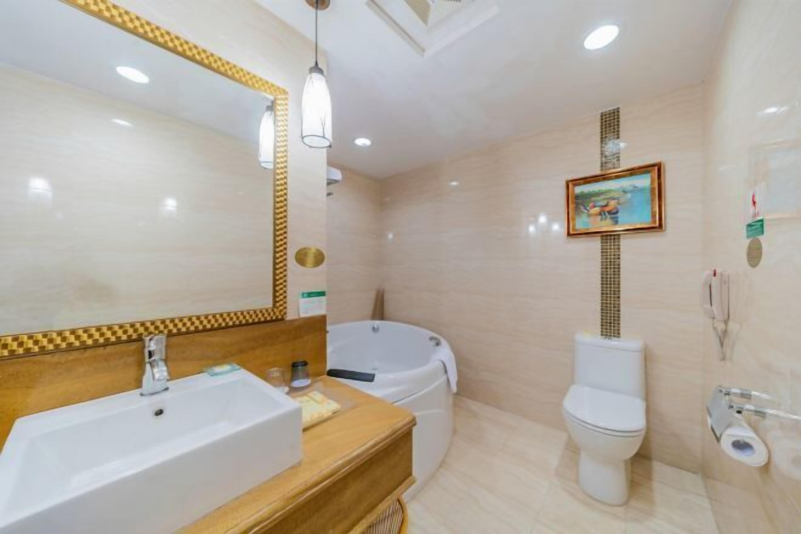 Un baño con lavamanos, espejo, bañera, inodoro y un cuadro en la pared.