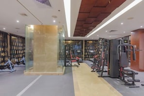 Une salle de sport équipée de matériel d’exercice, dotée d’une cloison en verre et d’un plafond en bois.