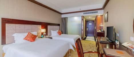 A hotel room with two beds, a desk, a chair, and a television.