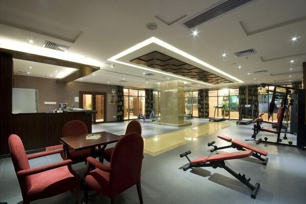 A hotel lobby with a reception desk, seating area, and exercise equipment. - Taishan Gaoye Hotel (Taishan)