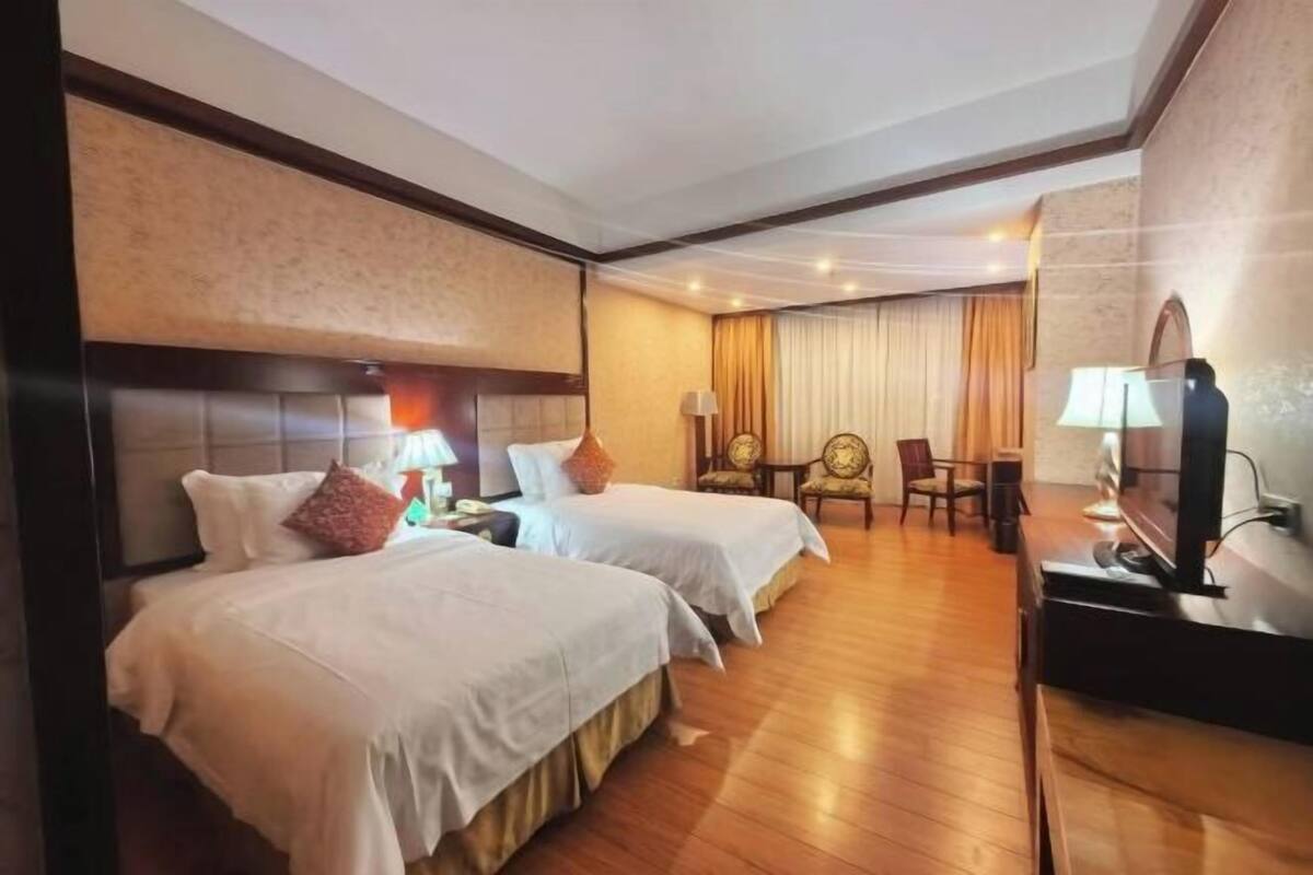 Habitación de hotel con dos camas, televisión, escritorio y silla.