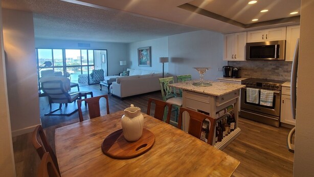 A modern kitchen with a central island, stainless steel appliances, and a dining area with a wooden table and chairs.