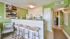 A kitchen with a bar area, white cabinets, and a green wall. - Pool Views, Good Times and Beach Vibes at Sea Breeze! (Galveston)