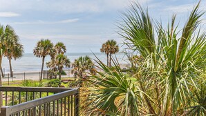 A balcony with a view of the ocean, palm trees, and a fence. - Pool Views, Good Times and Beach Vibes at Sea Breeze! (Galveston)