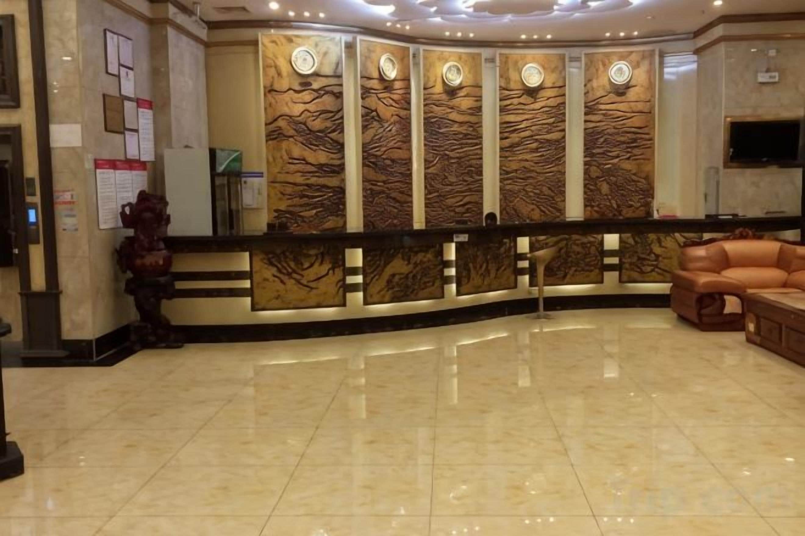 A reception area with a marble floor, a reception desk, and a seating area with a sofa.