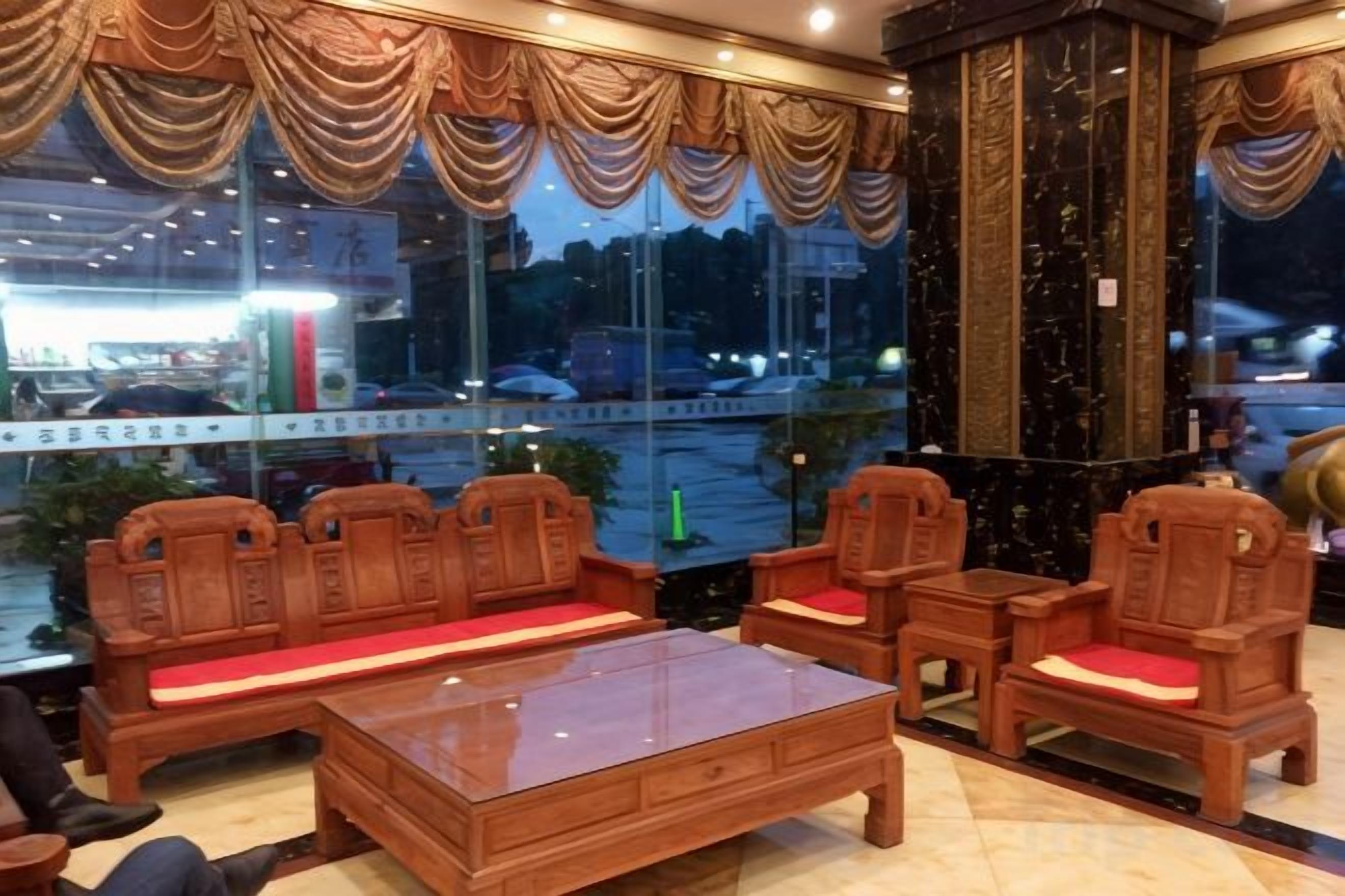 A lobby with a wooden sofa set, a coffee table, and a view of the street outside.