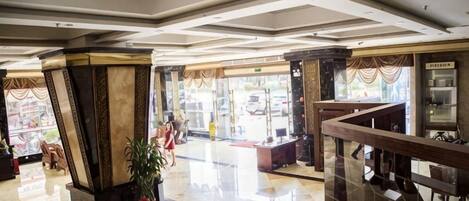 Un vestíbulo de hotel con mostrador de recepción, zona de estar y una escalera.