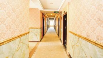 A hotel corridor with marble walls and patterned carpet.