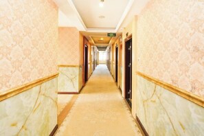 Corredor de hotel com paredes de mármore e carpete estampado.