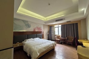 A hotel room with a bed, a seating area with chairs, a table, and a large window with curtains. - Huizhou Kaixuan Yuntian Hotel (Chenjiang Branch) (Huizhou)