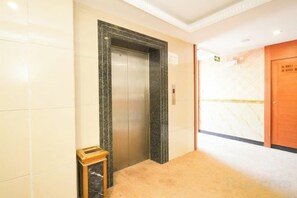 An elevator with a marble surround, a carpeted floor, and a wooden door with a sign. - Huizhou Kaixuan Yuntian Hotel (Chenjiang Branch) (Huizhou)