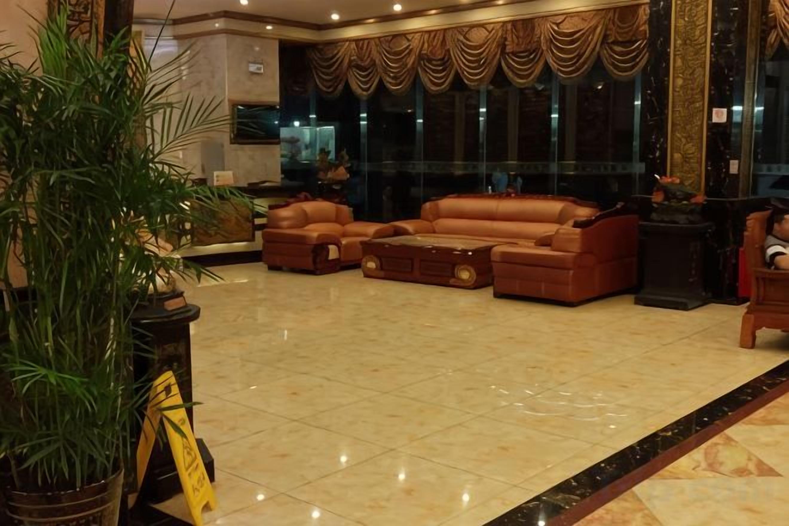 A spacious lobby with a large seating area, a reception desk, and a large window with curtains.