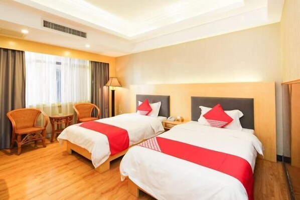 A hotel room with two beds, a sitting area with chairs, a lamp, and a window with curtains. - Huizhou Kaixuan Yuntian Hotel (Chenjiang Branch) (Huizhou)