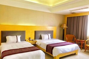 A hotel room with two beds, a nightstand, a lamp, a chair, and a window with curtains. - Huizhou Kaixuan Yuntian Hotel (Chenjiang Branch) (Huizhou)