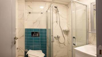 A modern bathroom with a glass-enclosed shower, a toilet, and a sink.