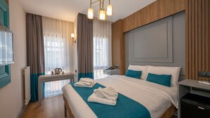 Una habitación de hotel con una cama grande, una mesita de noche, un escritorio y una silla.