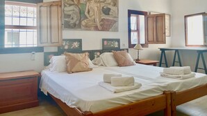 A double bed with a wooden frame, two nightstands, a painting above the bed, and a window with a view of trees. - Village house with patio (Altea)