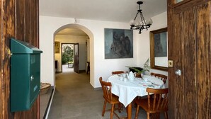 A dining area with a round table, wooden chairs, and a white tablecloth. There is a painting on the wall and a wooden cabinet to the left. - Village house with patio (Altea)