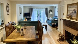 Ein geräumiges Wohnzimmer mit einem Holzespeisetisch, Sofas und einem Kamin.