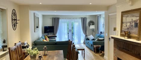 A spacious living room with a wooden dining table, sofas, and a fireplace.