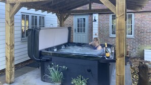 Ein Whirlpool unter einer Holzw pergola, im Hintergrund ein Ziegelhaus.