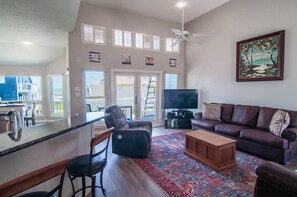 A living room with a television, a sofa, a coffee table, and a view of the outside.