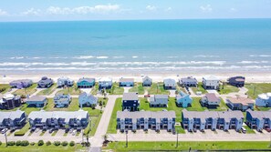A coastal residential area with houses, a beach, and a clear sky.